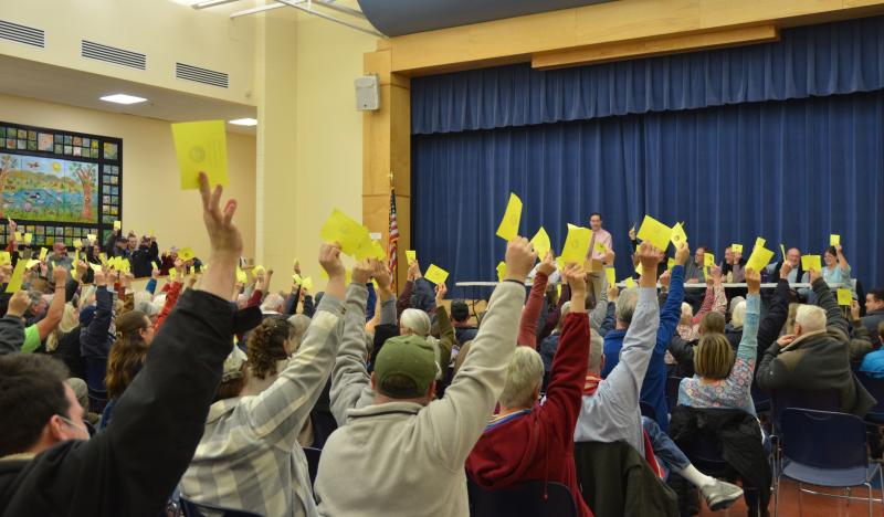 In a call to action following no discussion on the matter at hand Dec. 11, Moderator Andrew Hart asked Lincolnville voters to raise their yellow cards if they approved on a 180-day moratorium on nonresidential developments. The response was swift and unanimous in favor of the moratorium. (Photo by Lynda Clancy)