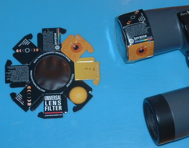 The picture on the left shows one filter as received. Once folded, the filter will snugly fit onto the lens of 50 mm binoculars as shown at the right. Retention is provided by tabs that project inward after folding. Follow the instructions for folding and be sure the tabs are in the inside, otherwise the filters won’t stay in place.