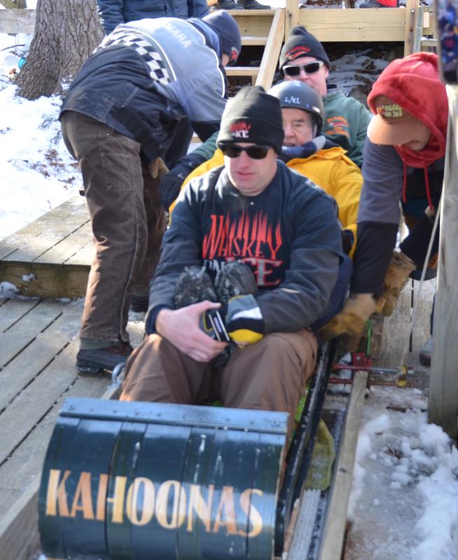 Bob Annis (in yellow), age 90, is protected by Tom Maxcy and Bruce Richards for his One More Ride. At age 2 and a half, he was bundled up and snuggled against his father on a toboggan, the youngest rider then to go down the newly built chute. His father, Blake Annis, was of the original crew that build the chute and Snow Bowl lodge in 1935-1936.