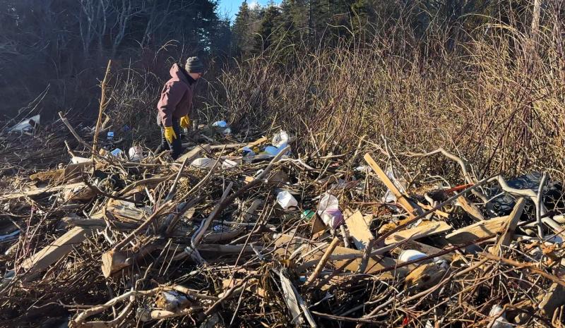 Stephanie Welch surveys debris and soil erosion from January storms. (Photo courtesy Maine Seacoast Mission)