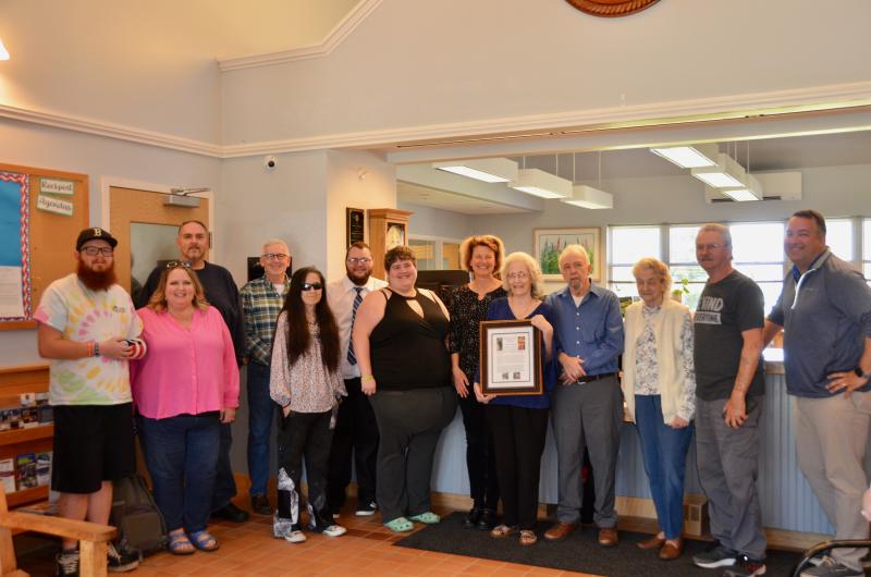 Linda Greenlaw, at the Rockport Town Office May 10, receives recognition as recipient of the annual town report dedication. She is surrounded by family and Rockport Select Board members. (Photo by Lynda Clancy)