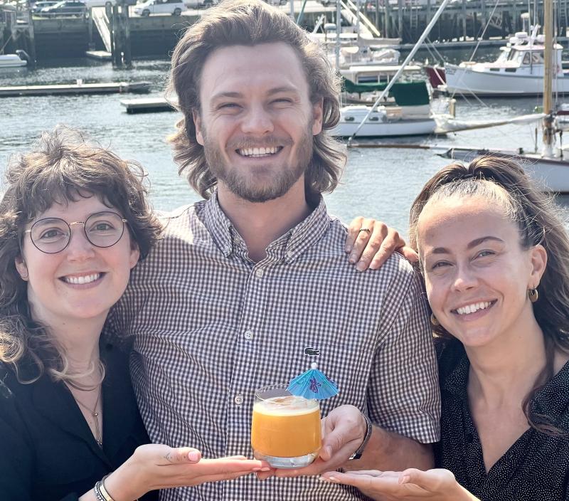 Salt Wharf Managers Mackenzie Gassett, Jake Smith, and Crystal Longo with their top-selling fresh passion fruit and pineapple "Vacation Land" cocktail that is their "Into the Light!" offering in July. (Photo by Patrisha McLean) Salt Wharf Managers Mackenzie Gassett, Jake Smith, and Crystal Longo with their top-selling fresh passion fruit and pineapple "Vacation Land" cocktail that is their "Into the Light!" offering in July. (Photo by Patrisha McLean)