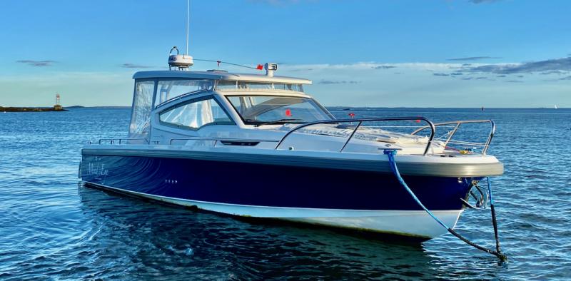 A well-equipped Nimbus W9 buttoned up against the Maine weather with full side curtains and an electrically powered sunroof. The mooring bridle takes advantage of both cleats on the bow. The electric anchor windlass can be operated with a remote control from anywhere on the boat; the remote also can run the bow thruster. The touches of orange are wind vanes on accessory whirligigs meant to deter gulls and cormorants. A well-equipped Nimbus W9 buttoned up against the Maine weather with full side curtains and an electrically powered sunroof. The mooring bridle takes advantage of both cleats on the bow. The electric anchor windlass can be operated with a remote control from anywhere on the boat; the remote also can run the bow thruster. The touches of orange are wind vanes on accessory whirligigs meant to deter gulls and cormorants.