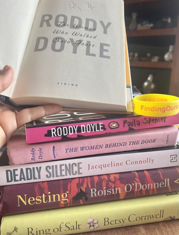 The autographed and first-edition copy of Roddy Doyle's The Woman Who Walked Into Doors that tops this stack was a gift to the nonprofit's CEO+Founder Patrisha McLean from her son Wyatt. The Irish authors of all of these books will be joining talks with Finding Our Voices through March. (Photo by Patrisha McLean) Stack of books with one book open to autograph on first page