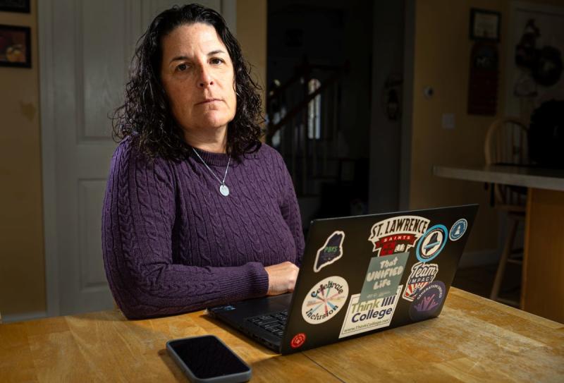 Carrie Woodcock, executive director of the Maine Parent Federation, sits at her kitchen table in Saco on October 23, where she works most days. Woodcock's organization provides free information, training and support to families of children with disabilities or special health care needs. She said she found declining school performance among students with disabilities and low incomes unsurprising, though she cautioned that testing doesn’t always show what students have learned. Photo by Troy R. Bennett. carrie woodcock sitting at a table.