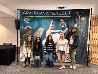 (Photo courtesy Julie Fajardo) Five attendees pose for a picture in front of a large banner of the event