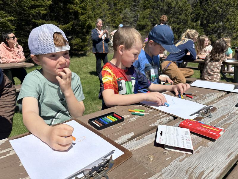 children work with crayons at a picnic table