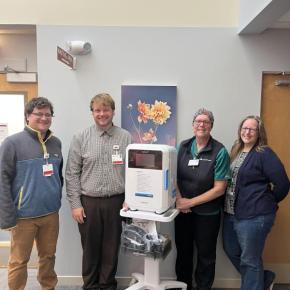Four people stand around a portable machine