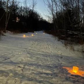 snow-covered trail with luminaries along the path