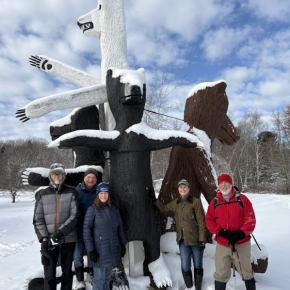 Winter hikers pose in front of a sculpture