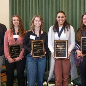 Seven young adults pose with award plaques