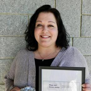 woman holds framed certificate, mug of chocolates