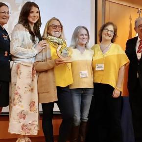 six adults pose with award