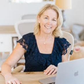 smiling woman looks up from laptop