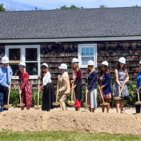multiple people hold shovels ladened with dirt