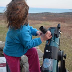 young child gripping telescope