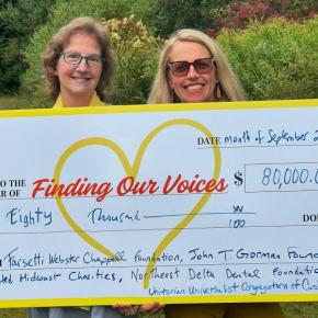two women pose with presentation check