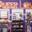 a look inside a thrift store, with a sign reading queer love hanging on the wall.