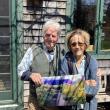 Barbara and Elliot are holding a painting of the garden in high season.