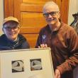 Rotarian Peter Lindquist (right) presents a dyptych pastel by the late Paul Plante to lucky winner Ali Dailey.