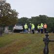 Car in cemetery as seen from driveway gate