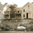 Large old house with garden in foreground and two children posing to the side for the picture