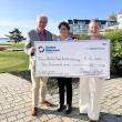 Man and two women pose while holding an oversized check