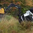 An excavator pushes gravel away from the bed of a dump truck