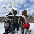 Winter hikers pose in front of a sculpture