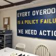 A sign that reads, “Every overdose is a policy failure. We need action.” 