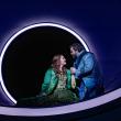 Woman, man in front of a moon-like orb