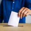 a man inserts his ballot into a box
