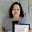 woman holds framed certificate, mug of chocolates