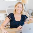 smiling woman looks up from laptop
