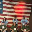 three sets of participants in front of flag