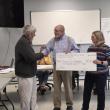 three adults stand with presentation check