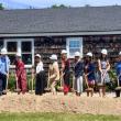 multiple people hold shovels ladened with dirt