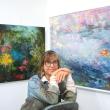 woman poses in front of paintings