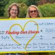two women pose with presentation check