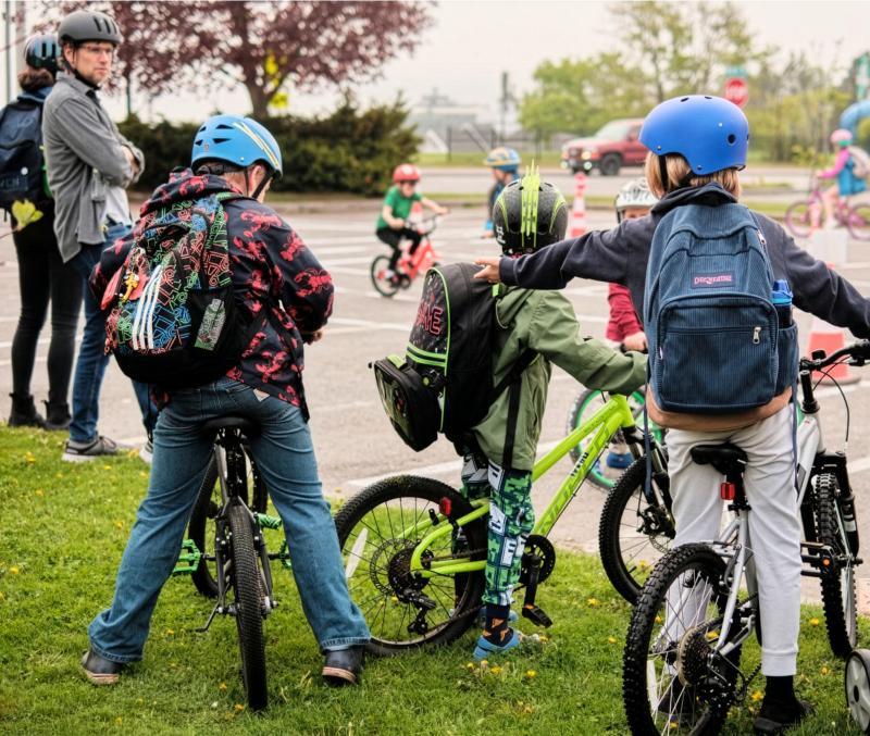 three backpack-wearing kids on bikes