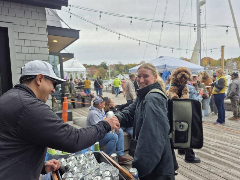 Mast Landing's Gabe Vickery hands Kathryn Rogers from Owls Head a beer as she, and her backpack buddy, Ziggy, enjoy the festival. Photo by Kay Stephens