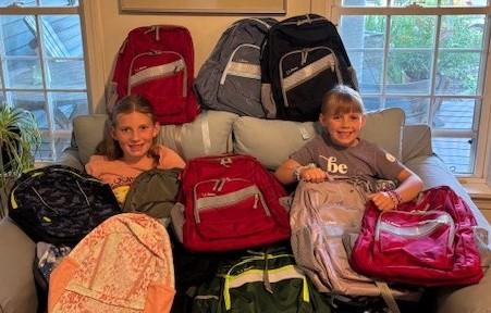 Two future Rotarians are all smiles as they help unload this year’s donation of 90 backpacks from L.L. Bean. (Photo courtesy West Bay Rotary)