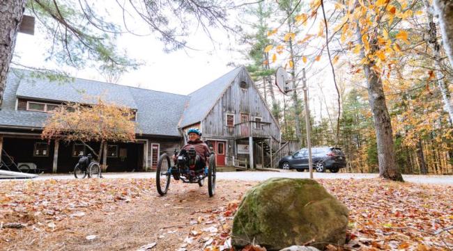 Woman rides an adaptive mountain bike away from a building