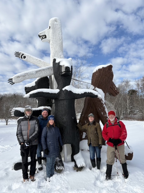 Winter hikers pose in front of a sculpture