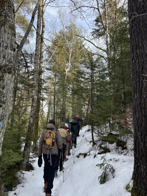 Line of hikers walk up a snow-covered trail