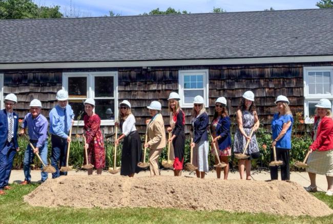multiple people hold shovels ladened with dirt