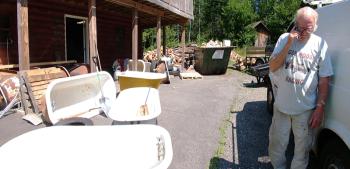 Mr. Tubs, surrounded by unrestored bathtubs takes a call outside his workshop. (Photo by Ethan Andrews) Mr. Tubs, surrounded by unrestored bathtubs takes a call outside his workshop. (Photo by Ethan Andrews)