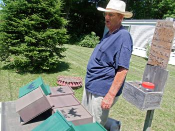 Adrian Turner surveys the traffic on Route 3 from behind a display of his homemade bat houses. (Photo by Ethan Andrews)