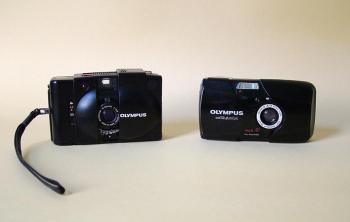 A pair of compact 35mm cameras, one of which the author tries to keep in a front pocket or otherwise nearby.