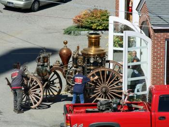 Many hands are needed Tuesday to move Camden's antique steam fire pumper.